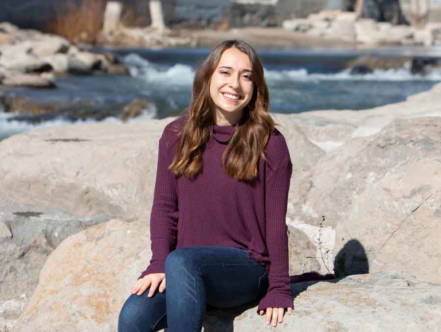 Lauren Mazurowski sits on some rocks by the river.