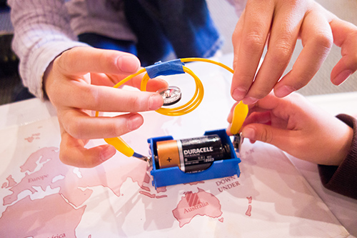 Teacher and student holding magnet and battery