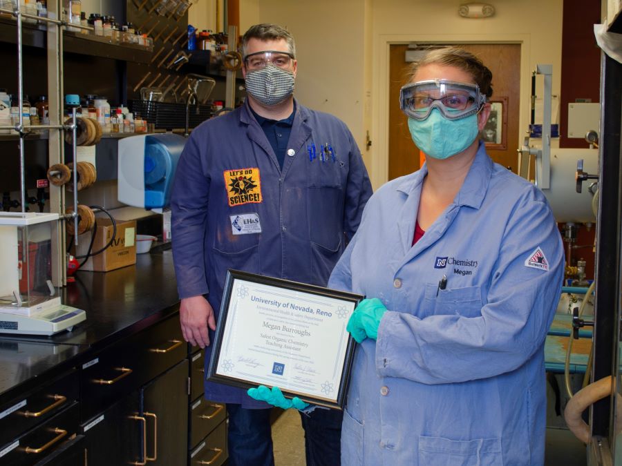 Laboratory training manager presents a certificate to teaching assistant in the lab, while both wear Personal Protective Equipment