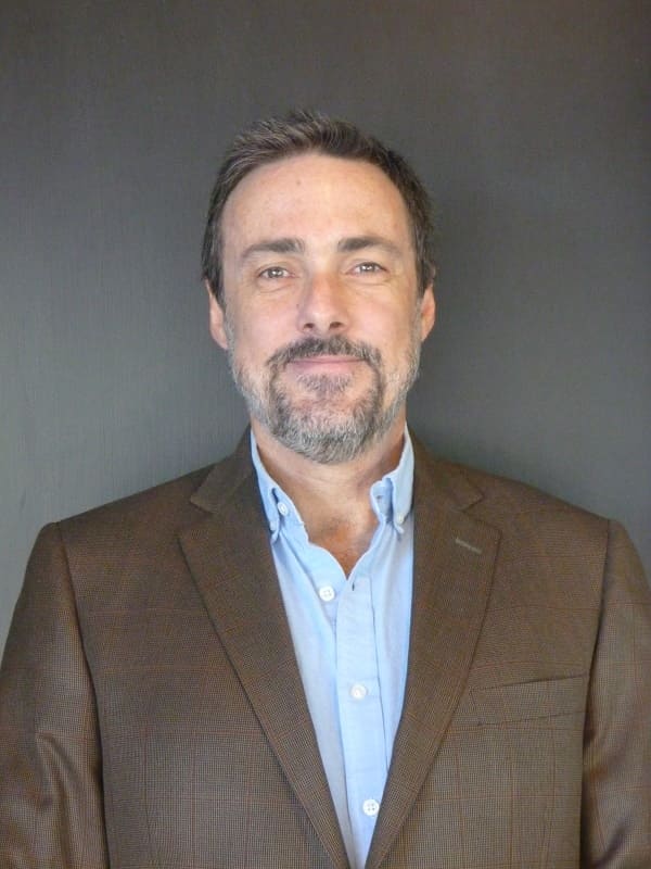 professional head shot of Christopher Morgan posed smiling in a suit