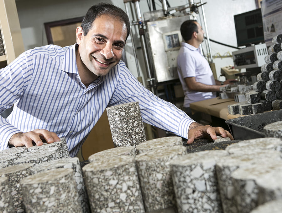 Elie Hajj inspects asphalt samples and smiles at camera