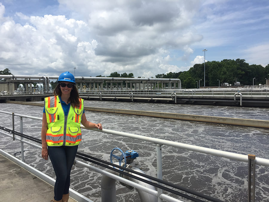 Woman in hard hat and vest stands next to water station