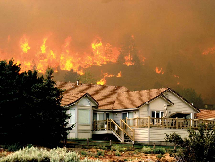 burning hillside behind a house
