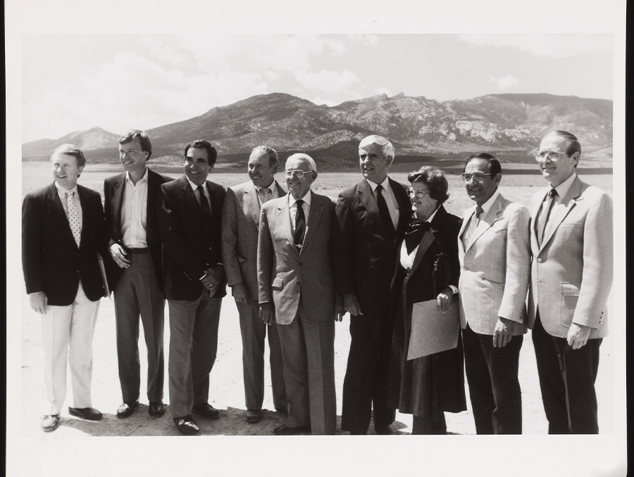 Black and While image of 8 men and one woman pose in from of the Great Basin National Park mountains. 