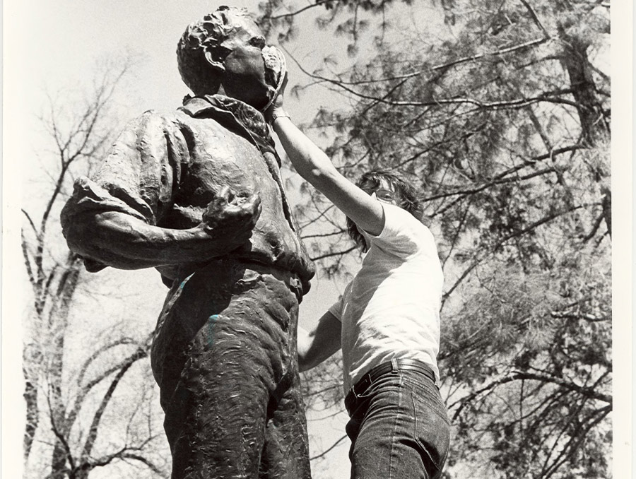 Black and white image of a man cleaning the Clarence Mackay statue in 1979