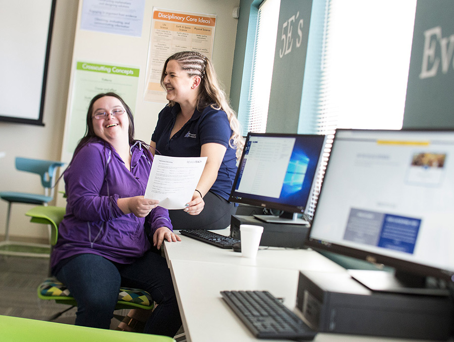 Two students sitting at a computer laughing