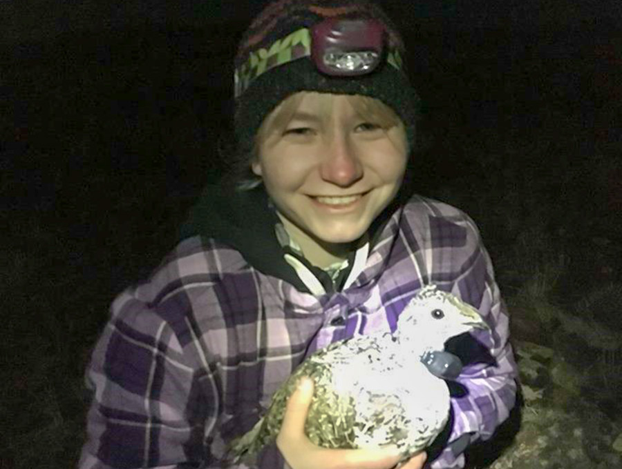 Lohman in the dark on a range wearing a headlamp holding a sage grouse