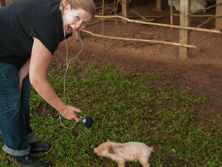 Alex Newman holds a microphone near a small pig.