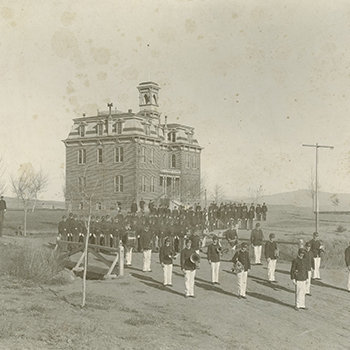 An old, black and white photo of Morrill Hall from 1901 with a uniformed cadet corps in front of it