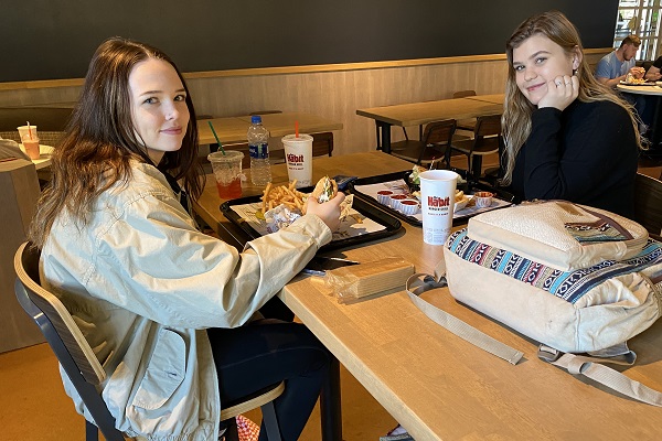 Two students sit at a table at the Habit Burger Grill with food