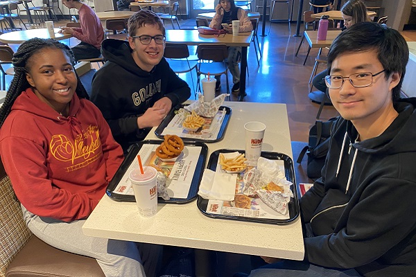 A trio of students sit together at the Habit Burger Grill with their food