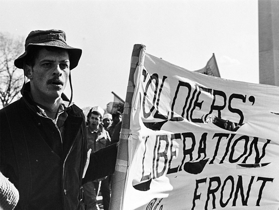 Man holds sign that reads "soldiers' liberation front"