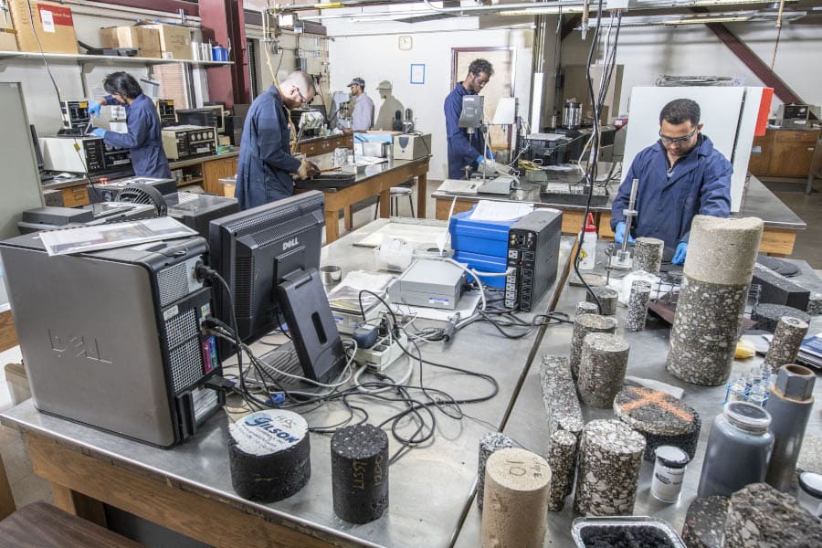 Five grad students work at various stations in a pavement lab.