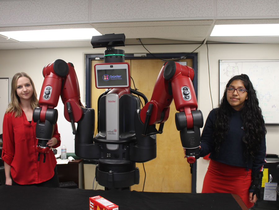 Two students pose with a robot in the lab.