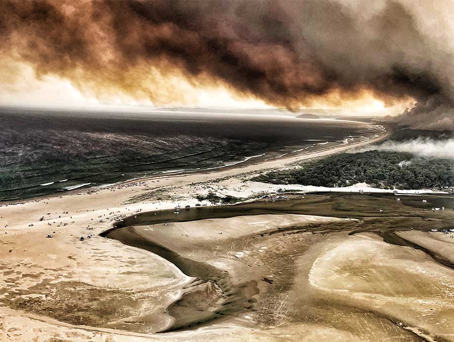 Fire raging and smoke billowing along a populated Australia coastline