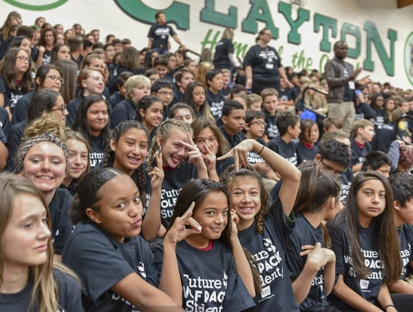 Bleachers full of middle school children wearing Nevada Wolf Pack gear and making the wolf sign with their hands