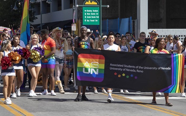 University students marching in the Northern Nevada Pride Parade behind a large ASUN banner