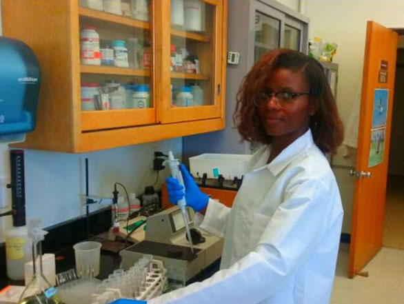 Christina wearing a lab coat analyzing samples in a lab