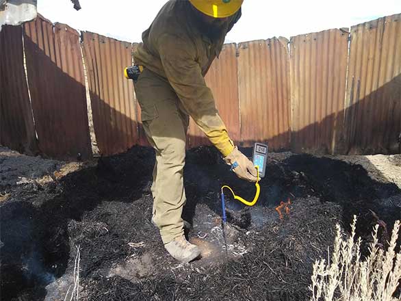 Man measuring temperature of soil after a fire