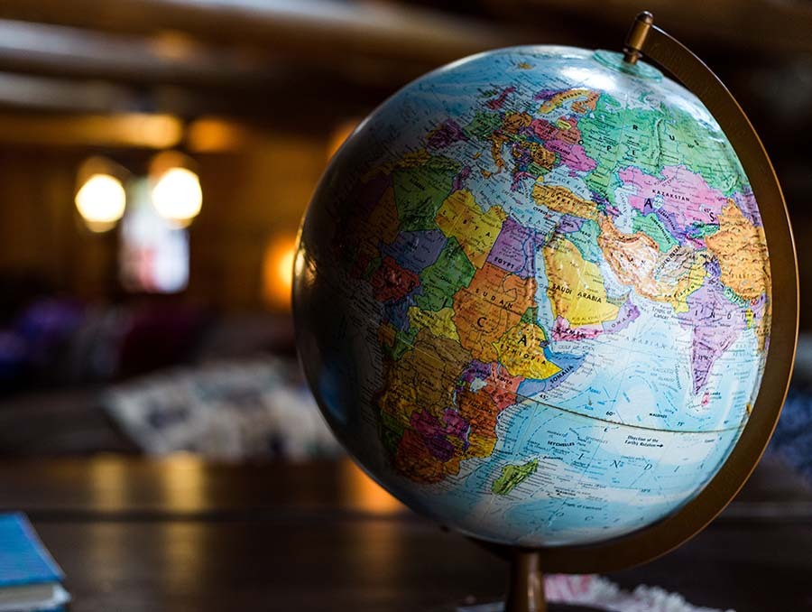 A globe of the world sit on top of a desk in a dark lit room