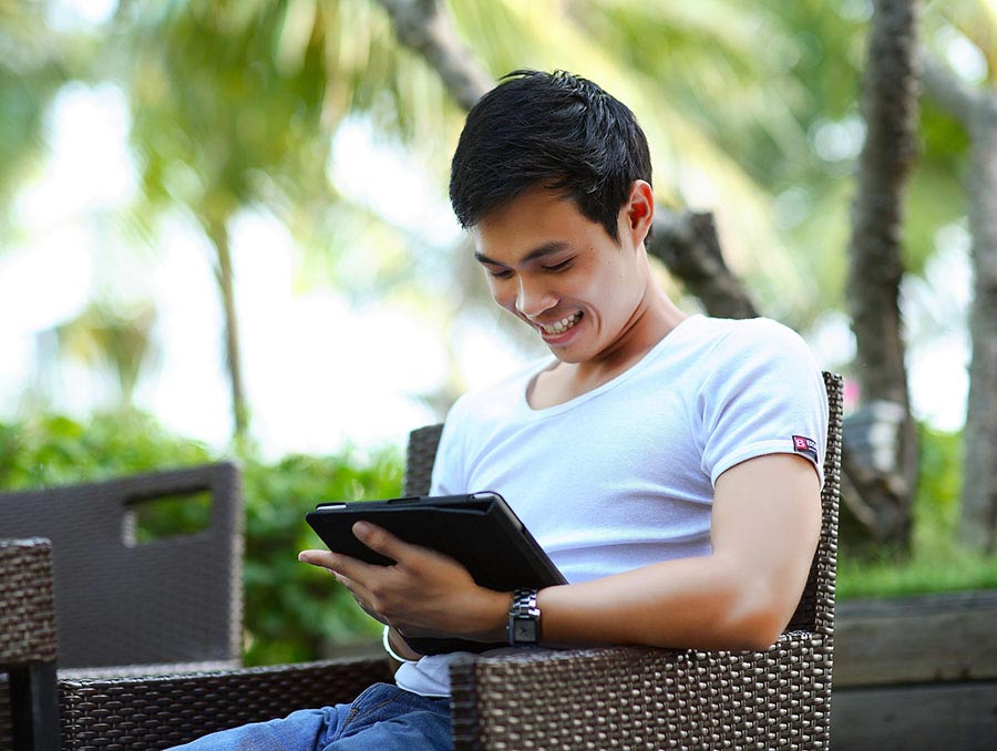 man sitting on a bench using a tablet