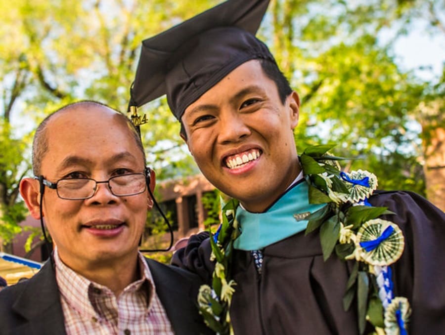 A father with his graduating son in full commencement regalia