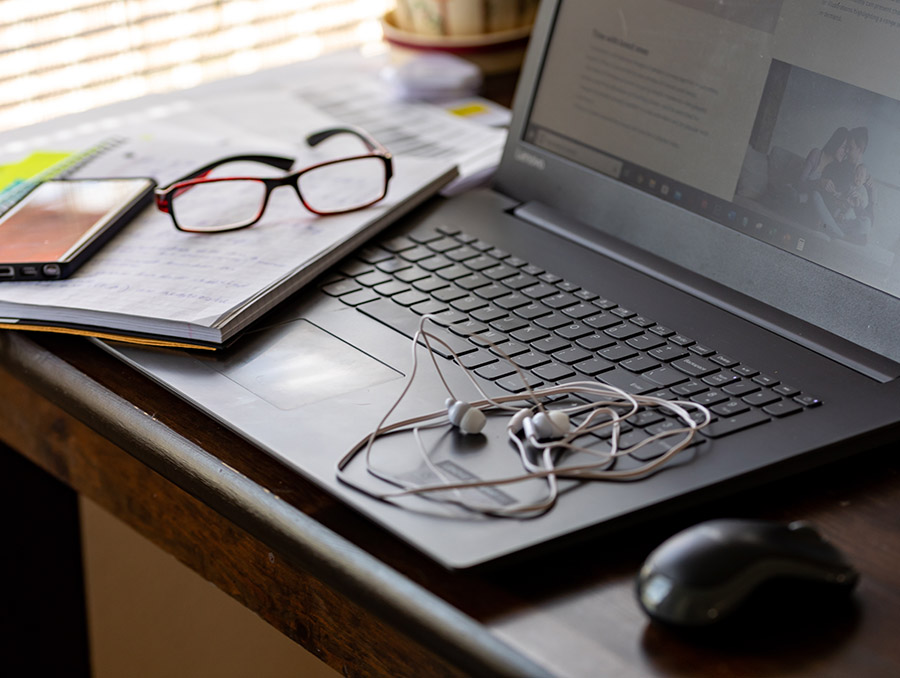 Laptop with glasses, paper, and earphones on keyboard. 