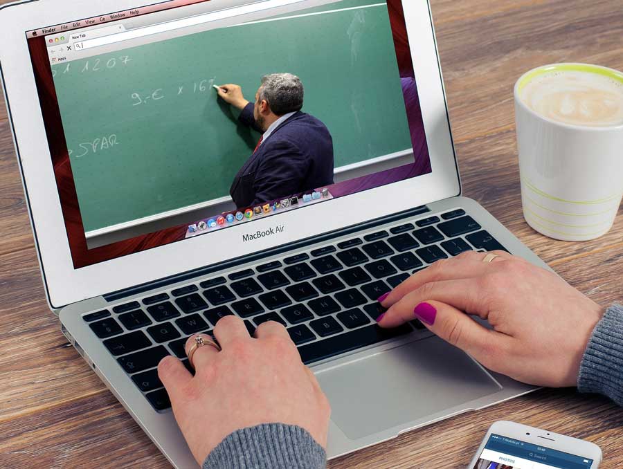 laptop screen showing man writing on green chalkboard