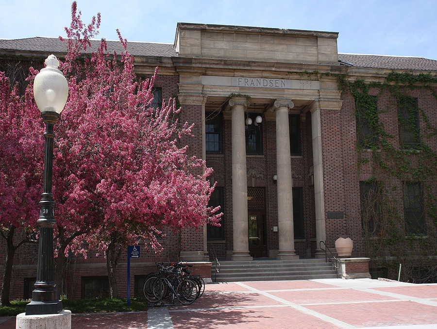 Frandsen Humanities Building with a pink tree out front during the spring