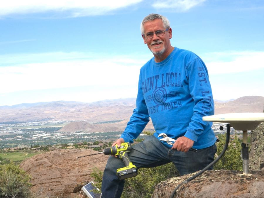 Professor Geoff Blewitt sits alongside a GPS station on a mountain that overlooks the valley of Reno and Sparks, Nev.