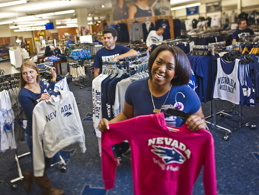 Students holding logoed apparel in The Nevada Wolf Shop