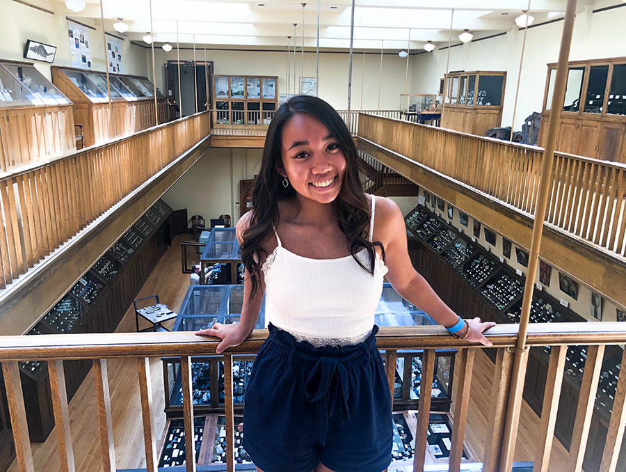 Maile standing in front of wood railling with museum in the background