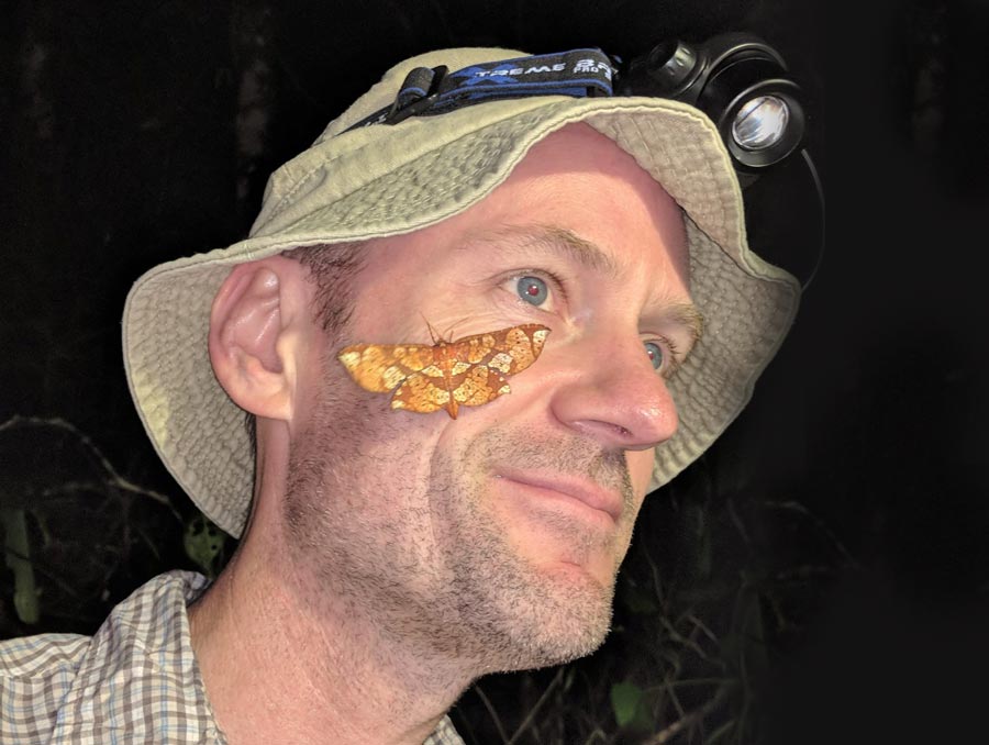 Photo of Matt Forister with a butterfly on his cheek.