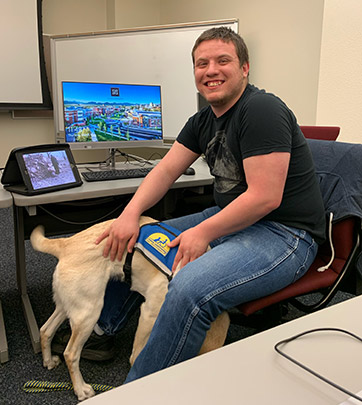 Student in a computer lab with seeing eye dog