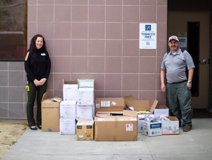 Jennie Parker and Chris Pritsos standing beside delivered personal protective equipment supplies