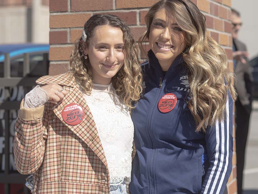 Students Claudia Feil, left, and Haley Cheatwood pose for a photo with Red Zone buttons on during the Red Zone campaign kick-off event.