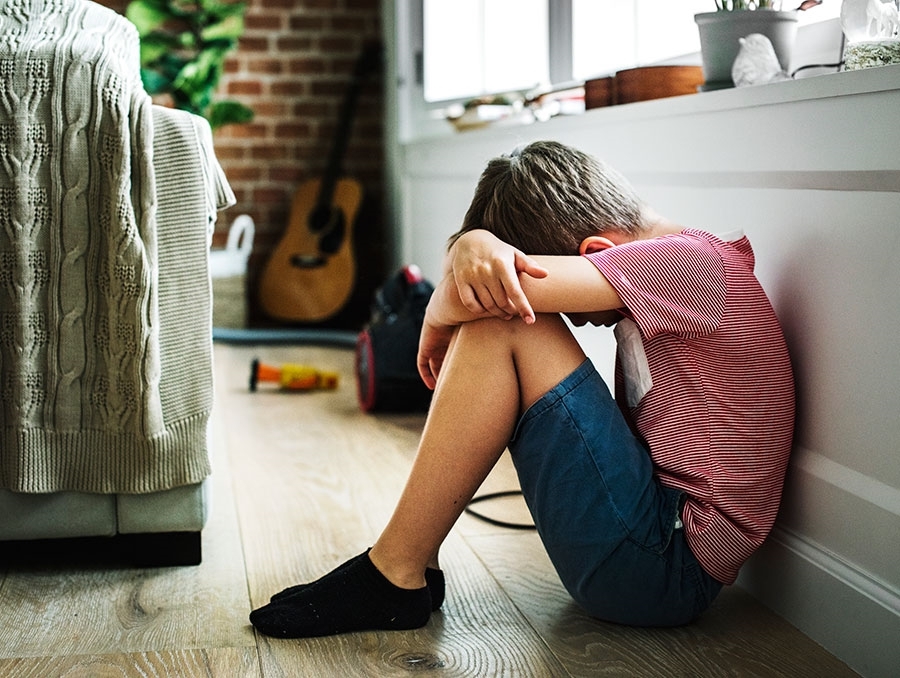 Sad child alone with their head down on the knees while sitting