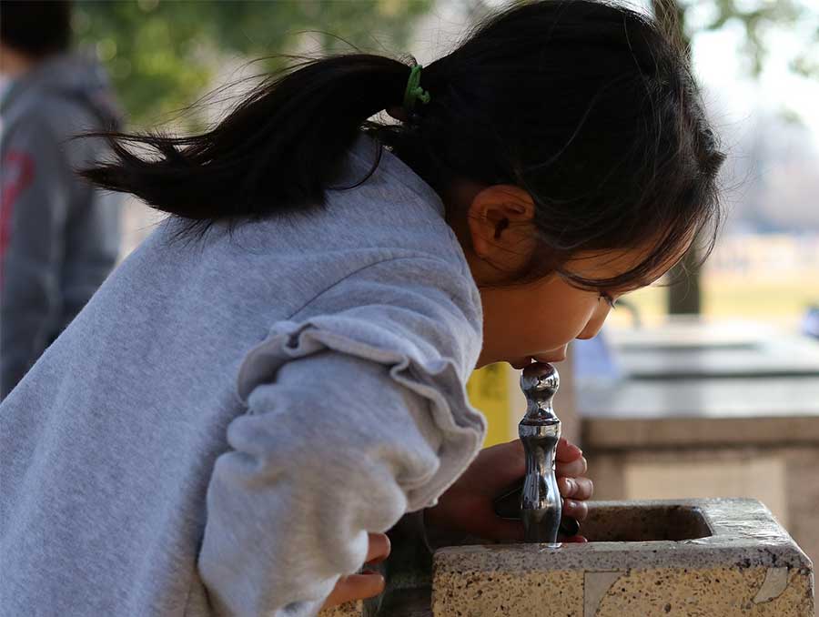 kid drinking water from fountain