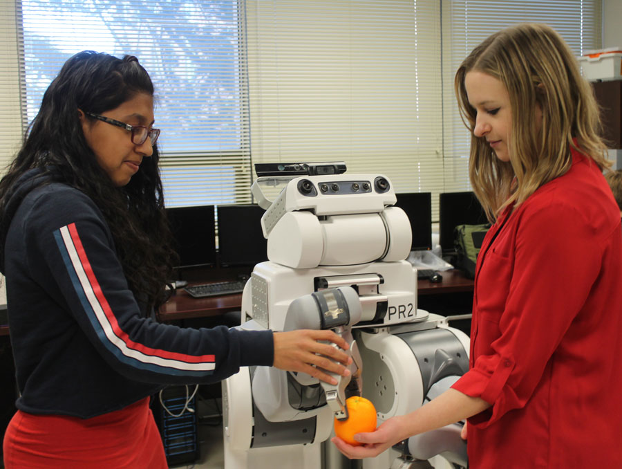 Two students demonstrating how a robot works with an orange.