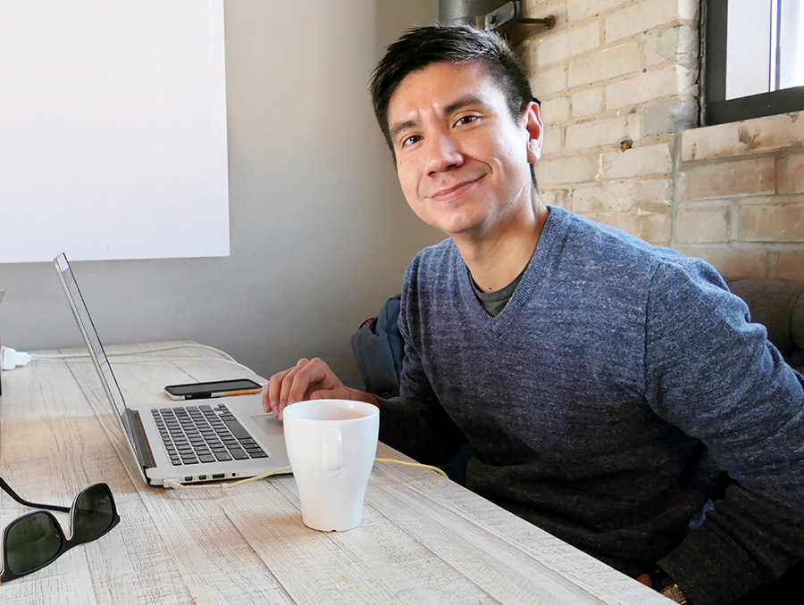 Ricardo Lopez sitting at a table with a cup of coffee and his laptop