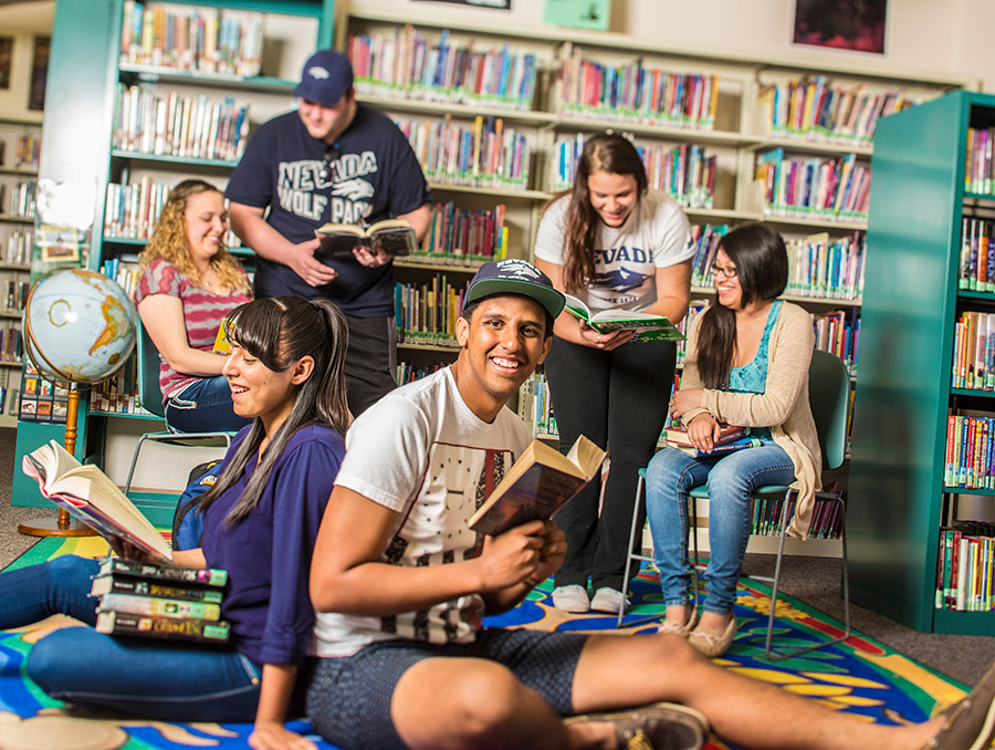 Group of students in a library reading books and interacting with each other.