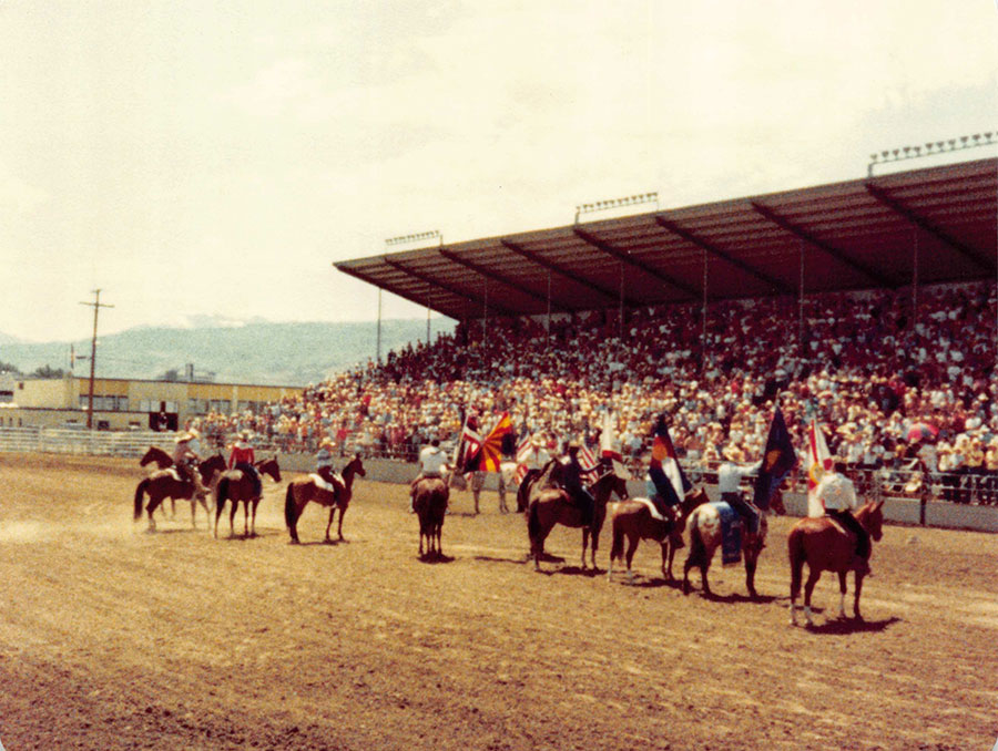 People ride on horses in an arena during the presentation of colors.