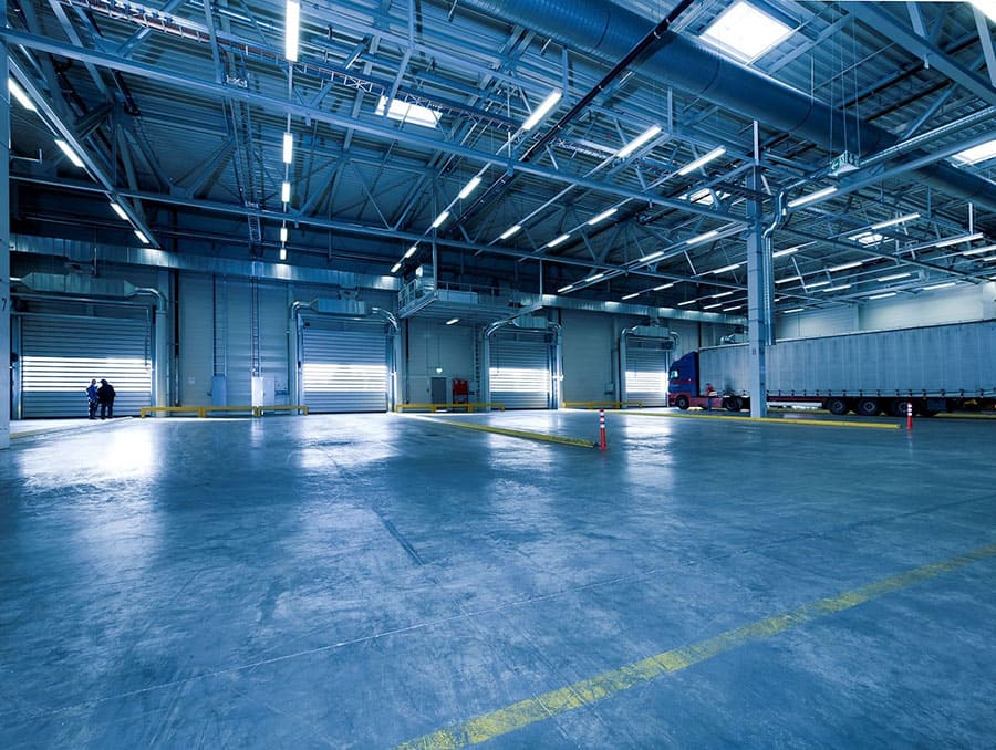 Large, mostly empty warehouse with one semi truck in the right corner.