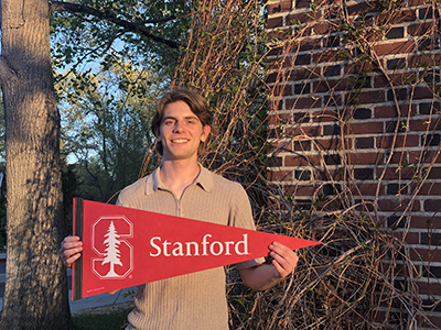 McNair student scholar Guglielmo Panelli stands holding Stanford flag