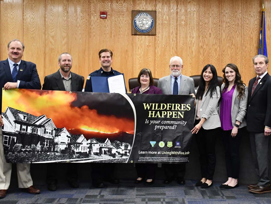 Carson City mayor holding a Nevada Wildfire Awareness Month banner alongside fire department and Living With Fire staff