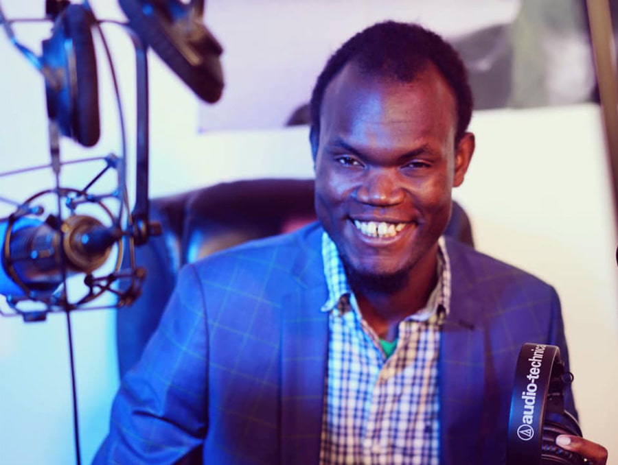 Apiyo (Nesta) sitting behind a desk smiling.