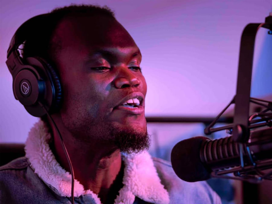 Robert Apiyo (Prince Nesta) talking into a microphone in a recording booth.