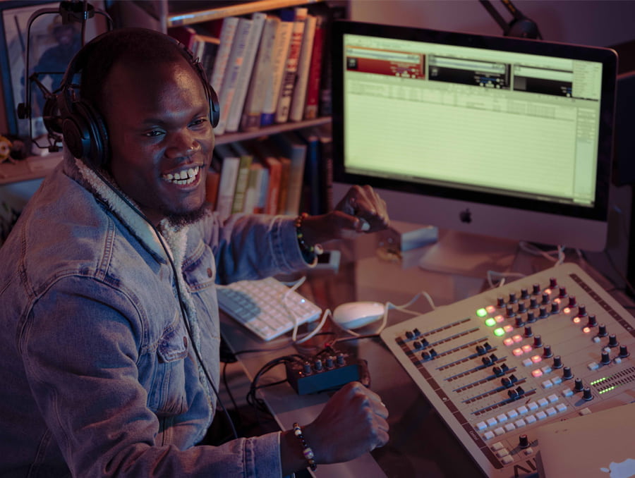 Robert Apiyo, also known as Prince Nesta, sitting in front of a computer and sound mixer.