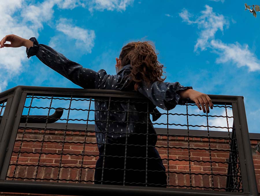 A person leans on an open staircase with their back to the camera looking up toward the blue sky. Photo by Caitlin Bell.