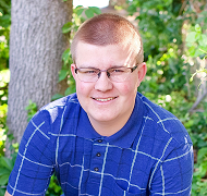 Portrait of a young man wearing glasses and a blue top